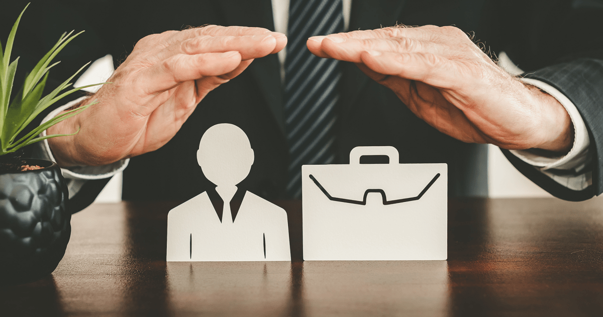Zakelijke verzekeringen: zakenman houdt zijn handen boven een icoon van een mens en een aktetas