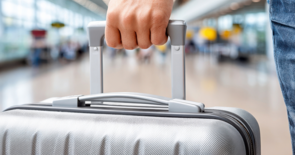 Persoon houdt koffer in zijn hand op een luchthaven