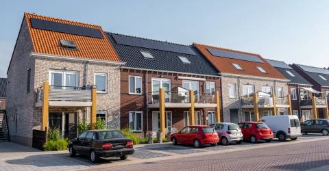 Nieuw gebouwde huizen met zonnepanelen op het dak met op de achtergrond een mooie blauwe lucht